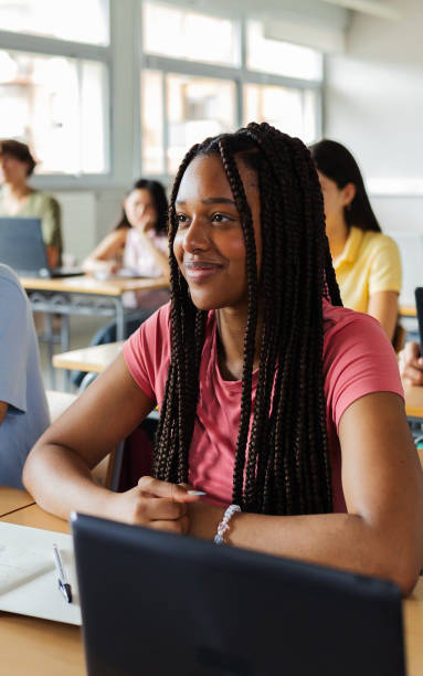 Portrait of smiling Latin American student girl listening teacher at high school stock photo