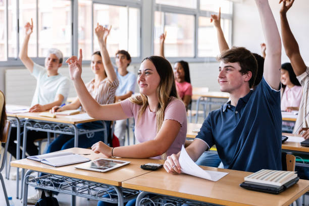 istock Group of high school students raising hands in classroom 2184618724