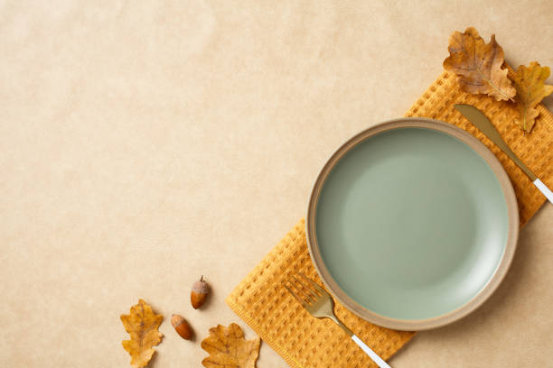 istock Ceramic plate, dried leaves, and acorns on a textured beige background. Thanksgiving dinner concept. Flat lay, top view, copy space 2184620690
