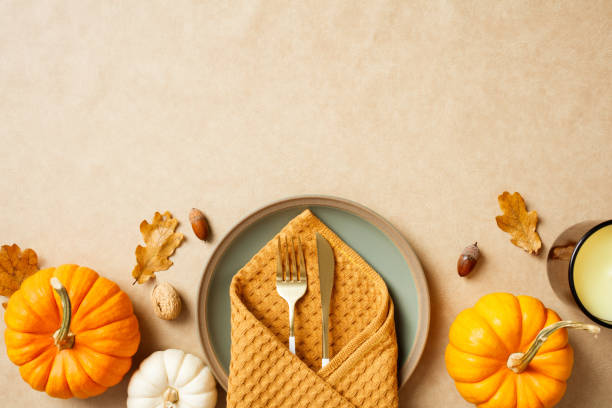 istock Thanksgiving table setting with pumpkins, leaves, and cutlery on a beige background. Flat lay, top view. 2184620737