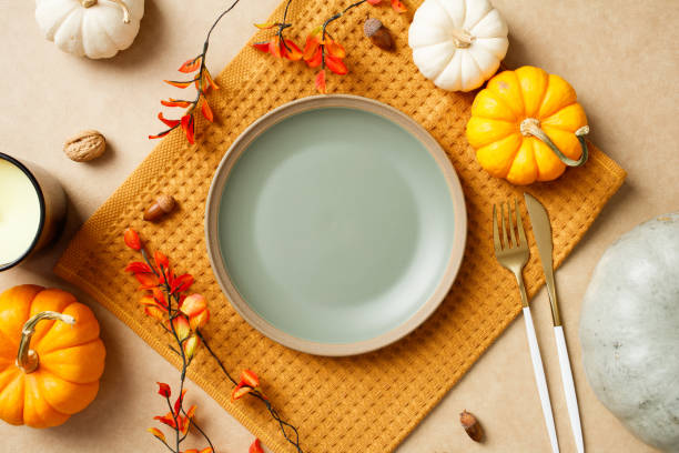 istock Autumn table setting with empty plate, pumpkins, leaves, acorns, and cutlery on a beige background. Perfect for Thanksgiving holiday celebration. 2184620755