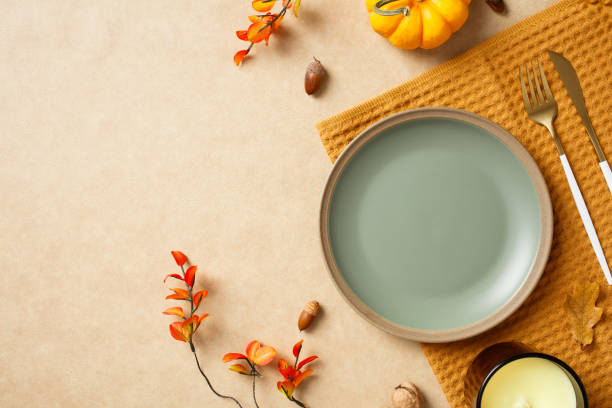istock Autumn dining table setting with pumpkins, leaves, acorns, and cutlery on a beige background. Perfect for Thanksgiving, fall decorations, and seasonal food presentations 2184620769