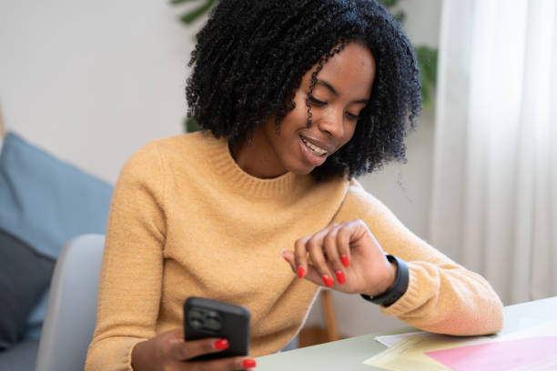 istock Young woman using smartwatch and smartphone at home office desk 2184621502