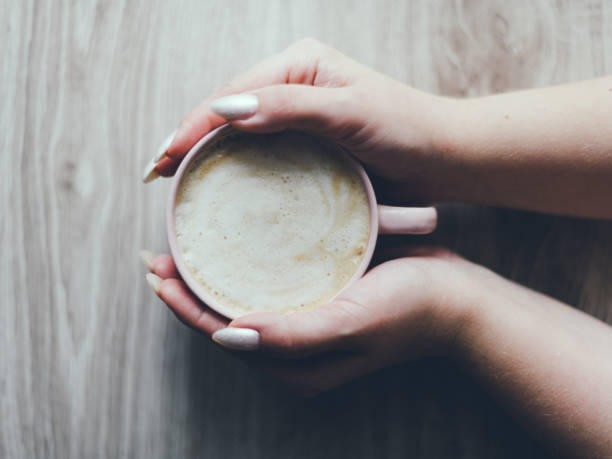 istock A hand holding a cup of coffee on a wooden table 2184626184