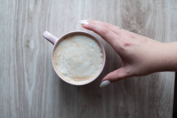istock A hand holding a cup of coffee on a wooden table 2184627135