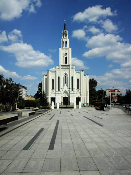 A large white church with a steeple and a cross on top. The sky is blue with some clouds Warsaw, Poland 08.06.2024