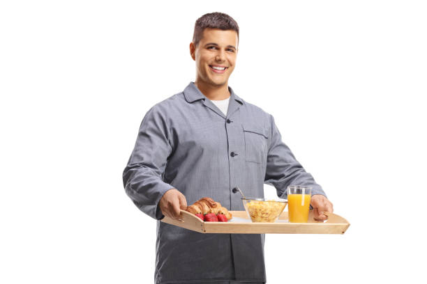 istock Smiling young man in pajamas holding a breakfast tray 2184629910