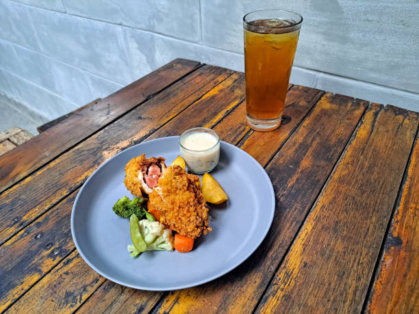 Tasty Chicken Cordon Bleu With Potato Wedges, Snow Peas, Brocolli, Carrot And Mushroom Sauce. Fresh Tea IcedIn Glass. Food And Drink Menu.