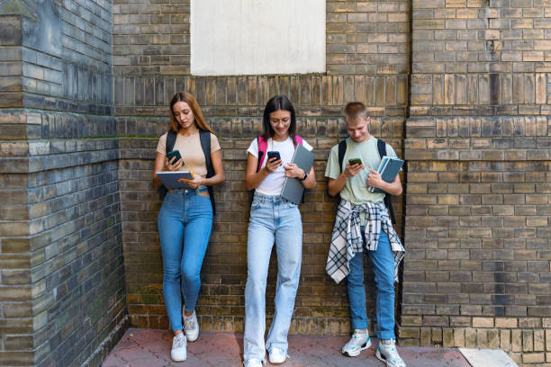 istock Students pause to check phones against brick background 2184632164