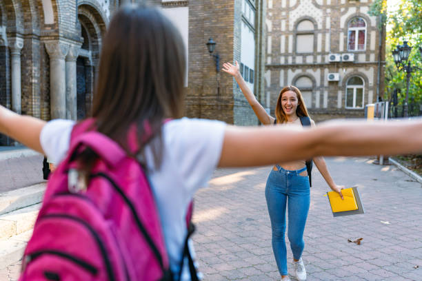 istock Two friends happily greeting each other on campus. 2184632380