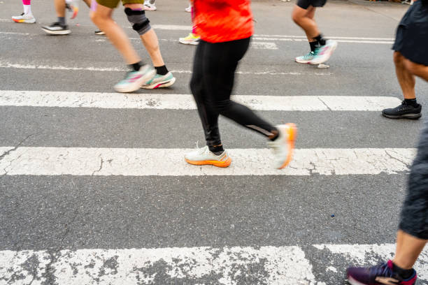This is a photo of the sneakers and legs of unrecognizable NYC Marathon runners running past a street crosswalk in a motion blur.