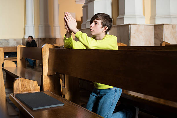 istock Catholic boy is praying to god in temple 2184632873