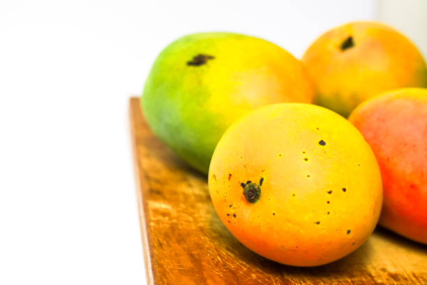 Mango fruit on cutting board isolated on white background, whole ripe yellow apple mango fruit