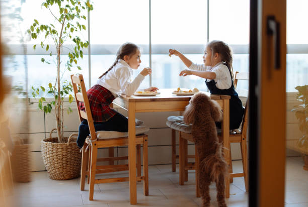 Cute children having fun while eating fish and chips at home