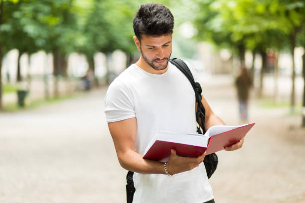 istock Young male student reading a book in a park 2184634279