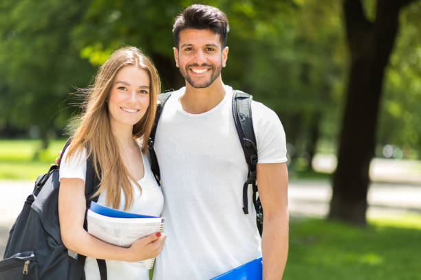 Two smiling students standing together on a sunny university campus