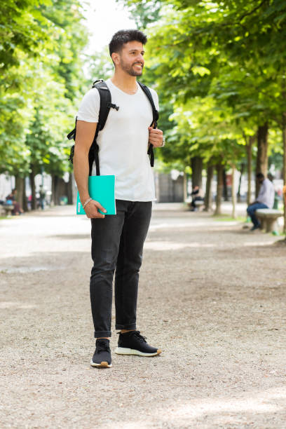 istock Young male student smiling and holding a book in a park 2184636289