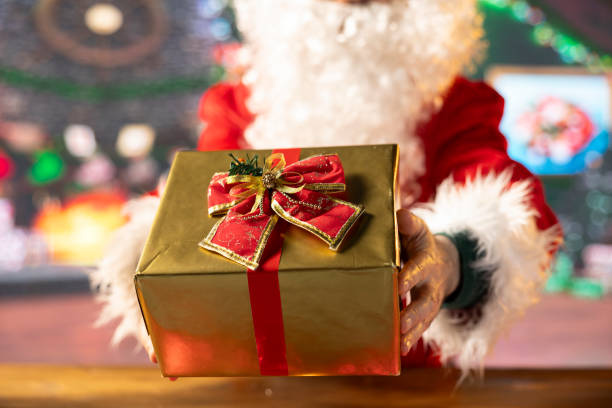 istock Father Christmas decorates a wrapped present box with festive wrapping paper 2184637049