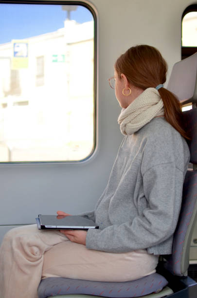 istock A woman is sitting on a train with a tablet in her lap 2184640366