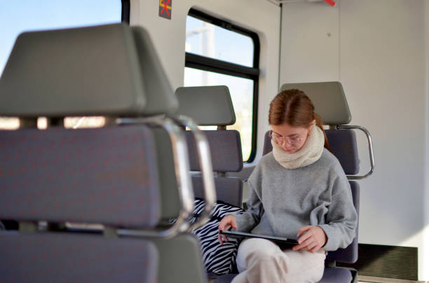 istock A girl is sitting on a train with a tablet in her lap 2184640368