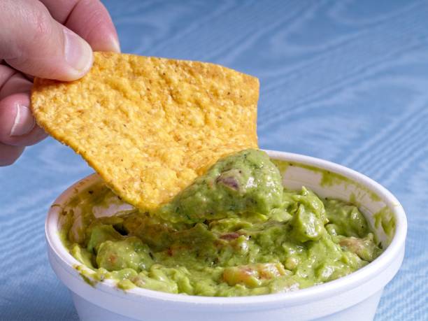 istock Hand and tortilla chip scoop out fresh guacamole 2184640406