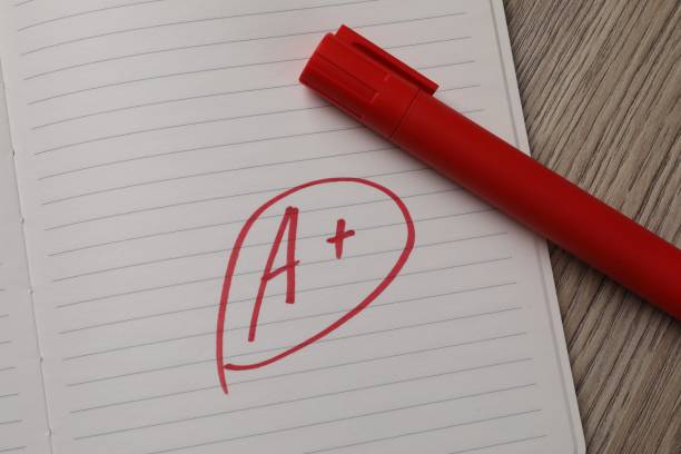 istock School grade. Red letter A with plus symbol on notebook paper and marker on table, top view 2184640672
