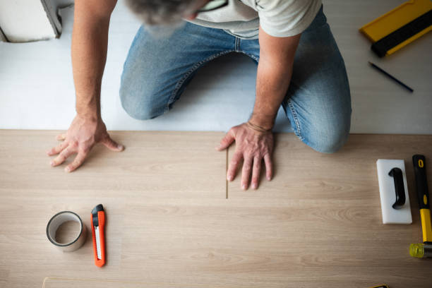 Construction worker installing new laminate or parquet flooring during home improvement work