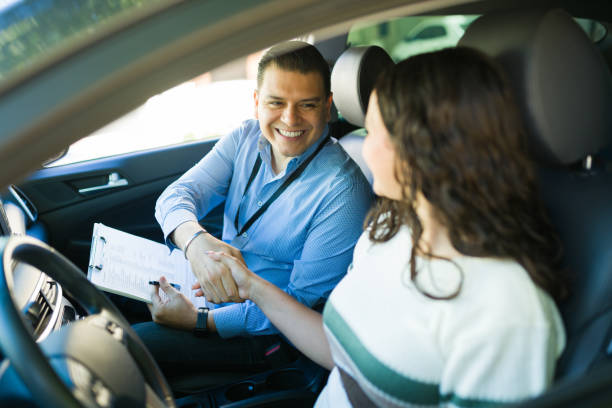 istock Happy driving instructor shaking hands with his student after passing the driving test inside a car 2184648517