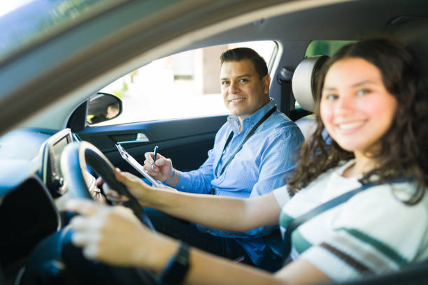 istock Teen girl learning to drive with a driving instructor taking notes during a driving lesson 2184648584