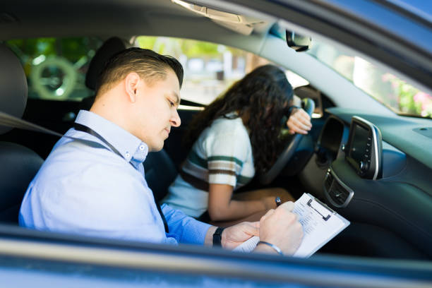 istock Serious driving instructor evaluating teenager during driving test, taking notes on a clipboard while she fails her test 2184648642