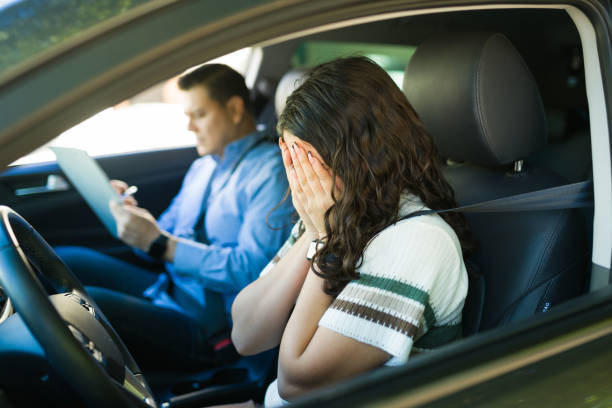 istock Anxious teen hiding her face after unsuccessful driving test as instructor records errors during road lesson 2184648664