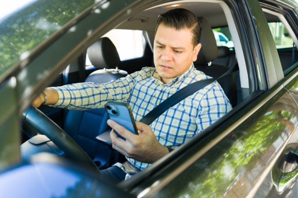 istock Latin businessman on his phone while driving, risking an accident 2184654266