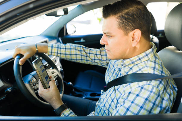 istock Distracted man texting while driving, risking an accident, and wearing a seat belt 2184654269