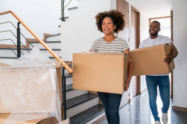 Happy couple carrying boxes while moving house