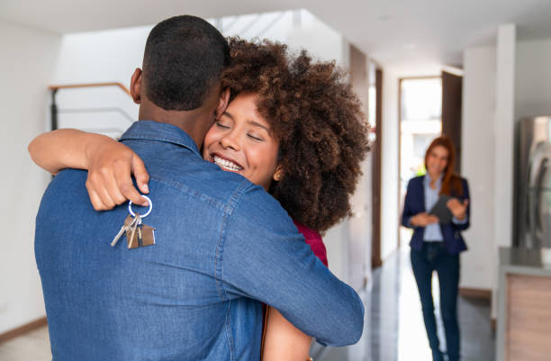 istock Couple hugging while celebrating buying a house and holding the keys 2184665154