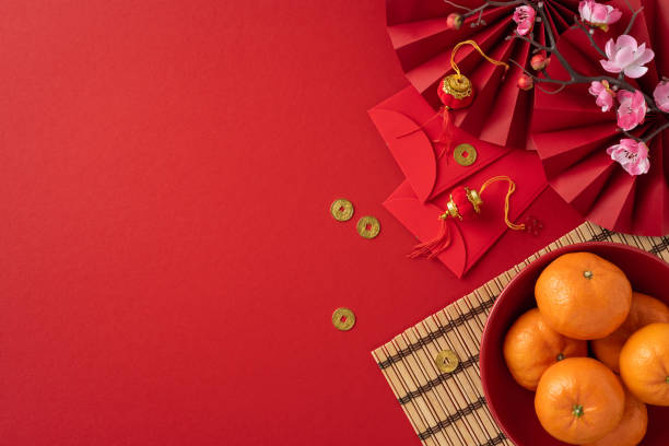 istock A vibrant Chinese New Year setup featuring oranges, red envelopes, golden coins, and beautiful blossoms on a red background. This festive arrangement symbolizes prosperity and good fortune 2184681027