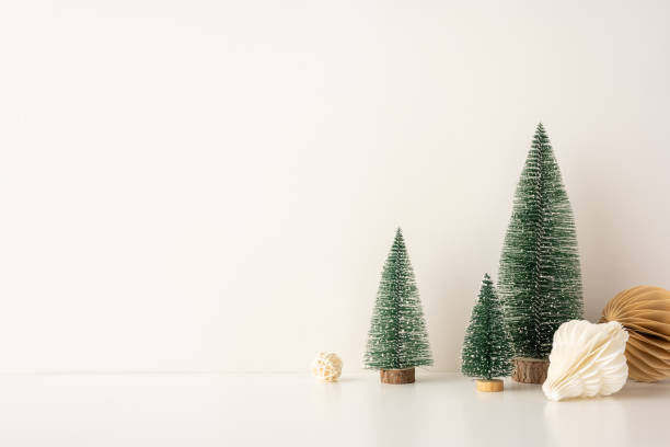 istock Decorative side view setup with mini snow-covered Christmas trees and paper ornaments in a Scandinavian minimalist style, placed against a neutral backdrop 2184681124