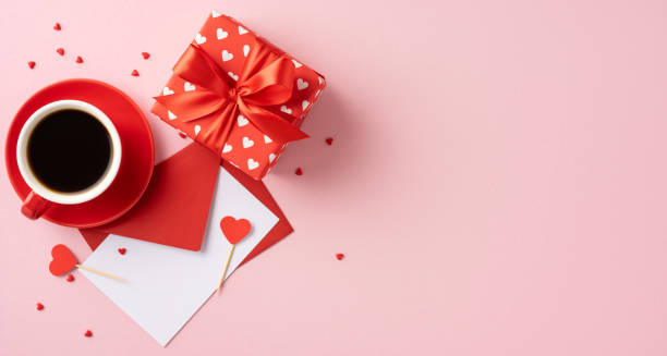 istock Romantic Valentine's Day scene featuring a red coffee cup, heart-themed gift, and envelopes on a pink background, evoking feelings of love and affection. 2184681126