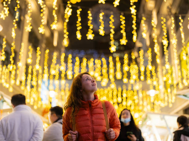 Woman looking with awe at illuminated decorations on Christmas market at night
