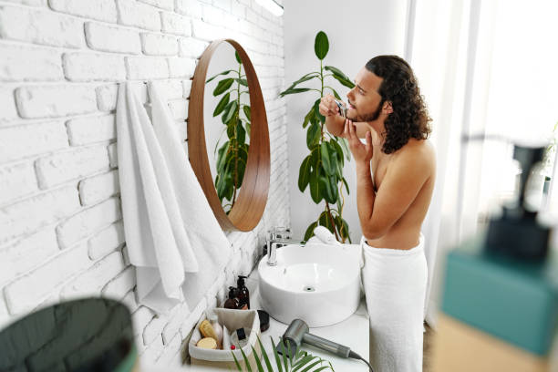 istock A man with curly hair grooming himself in the bathroom while looking into a round mirror 2184689492
