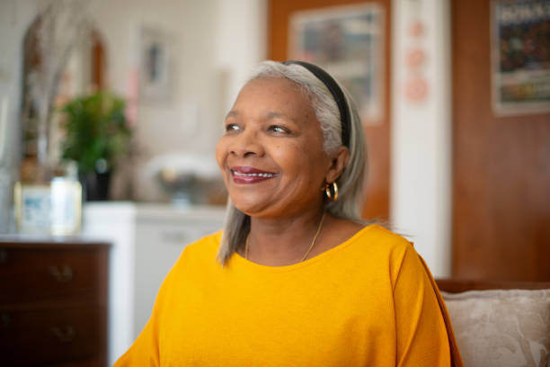 istock Senior African woman, reflection and home with smile on sofa for thinking, memory or relax in living room. Elderly person, inspiration and perspective with insight, happy or morning on couch in house 2184691679
