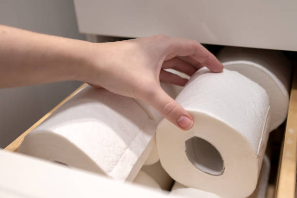 istock Hand selecting and lifting toilet paper roll from organized bathroom drawer storage, Managing essential supplies in modern white cabinet for home hygiene maintenance 2184693467
