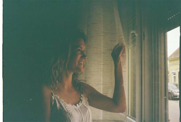istock Beautiful woman looking through the window 2184695959