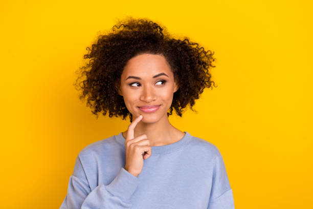 istock Photo of cute tricky curly girl dressed blue pullover finger chin looking empty space isolated yellow color background 2184696250