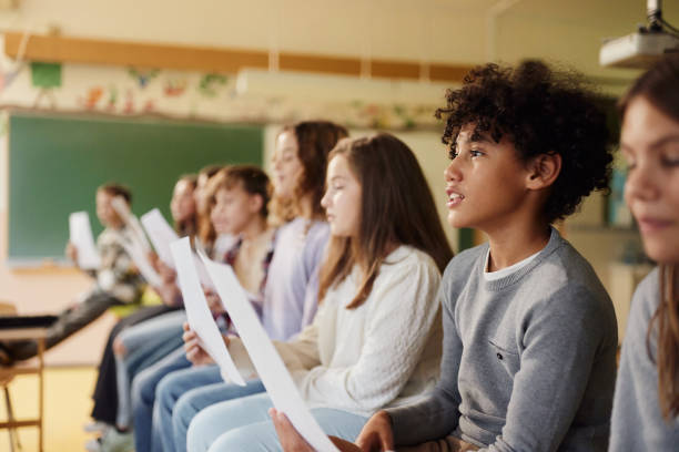 istock School kids practicing with sheet music on a class at school. 2184697768