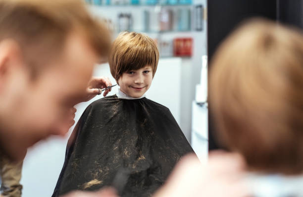 istock Cheerful Young Boy Getting Haircut at Modern Salon 2184697891