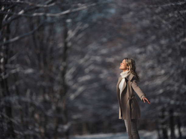 Carefree woman enjoying with her eyes closed and arms outstretched during winter day in the forest. Copy space. Photographed in medium format.