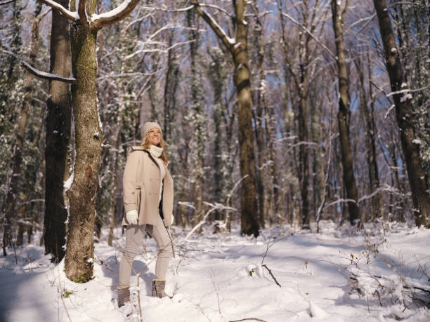 Happy woman enjoying while spending a winter day on snow in the forest. Photographed in medium format.