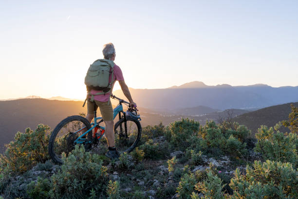 istock Mature mountain biker rides hills at sunrise 2184701713