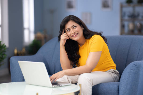 istock Woman using laptop sitting on sofa at home stock photo 2184705363